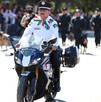 En la imagen se ve a un oficial de tránsito vestido de blanco con negro en una motocicleta y a lo lejos se ven más elementos de seguridad.