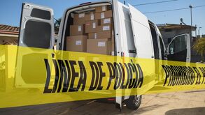 Vehículo de paquetería y linea de policía acordonando el área.