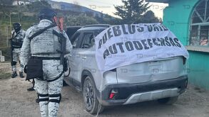 Elemento de la Guardia Nacional parado junto a un vehículo baleado, presuntamente de autodefensas.