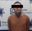 Hombre tatuado y  con playera naranja con los ojos tapados