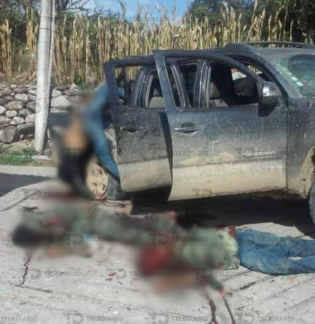 Hombres muertos alrededor de una camioneta baleada y cubierta de sangre.