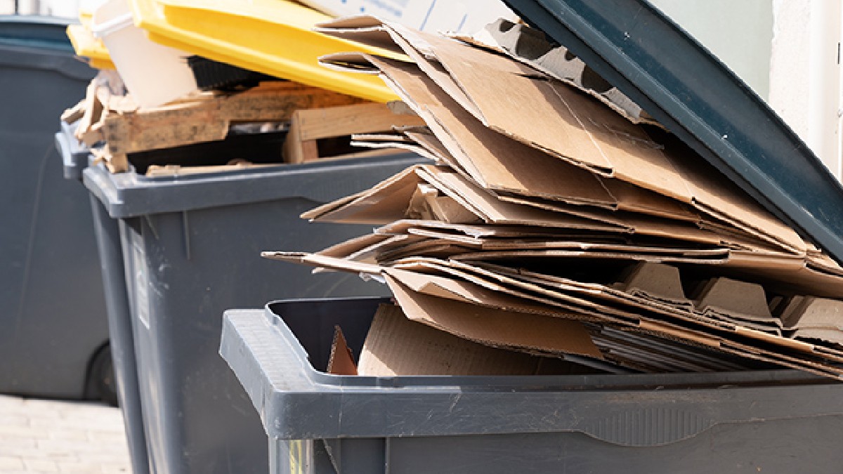 Contenedor de basura color gris con varias carpetas amarillas adentro