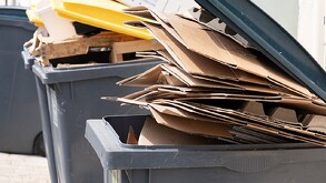 Contenedor de basura color gris con varias carpetas amarillas adentro