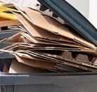 Contenedor de basura color gris con varias carpetas amarillas adentro