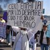 Mujer sostiene una pancarta durante una manifestación en una carretera.