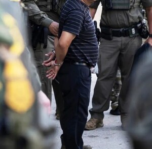 Elementos de la Policía de Chicago realizando la detención de un hombre de 40 años con esposas colocadas y las manos en la espalda