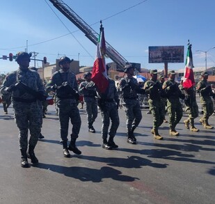 En la imagen se ven a soldados desfilar y personas los observan.