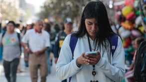 Mujer caminando con el celular en la mano, mientras responde un mensaje.