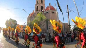 Grupo de personas con vestimenta de danzantes, antes de entrar al templo de la virgen de Guadalupe en Gómez Palacio.