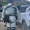 Elemento de la Guardia Nacional parado junto a un vehículo baleado, presuntamente de autodefensas.