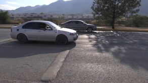 Se observa un carro gris pasando sobre un reductor de velocidad.