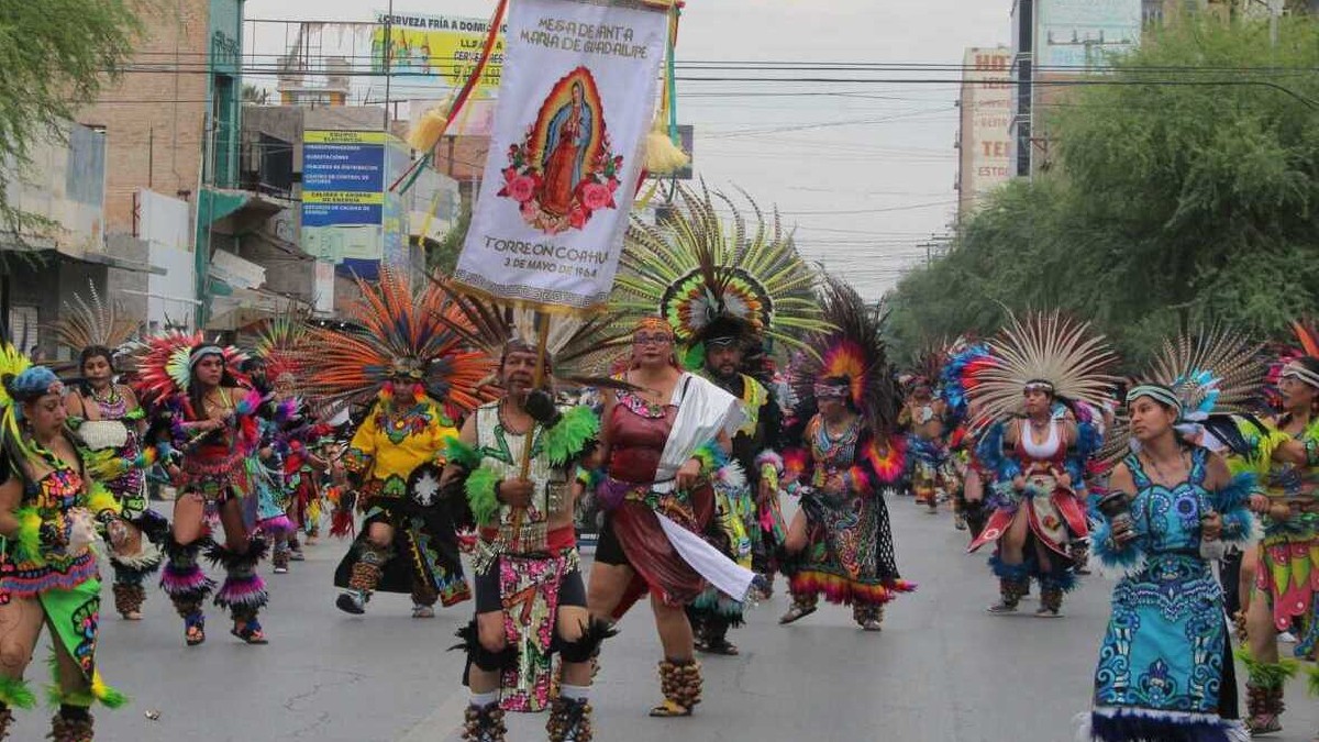 Grupo de personas caracterizados con ropa de danza azteca y un estandarte de la Virgen de Guadalupe