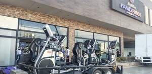 Varios aparatos de gimnasio están afuera de un gimnasio con letrero de Family Fitness.