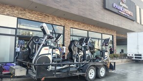 Varios aparatos de gimnasio están afuera de un gimnasio con letrero de Family Fitness.