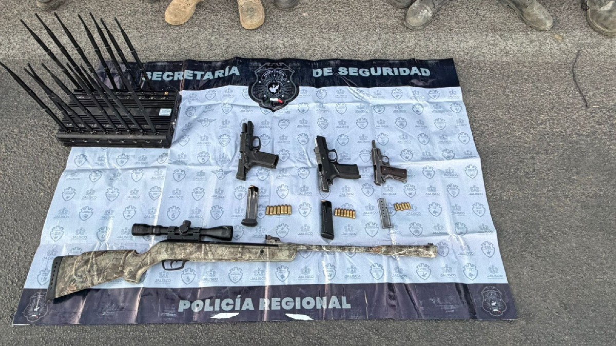 Dos policías con equipo táctico flanquean a cinco detenidos (rostros censurados) en un camino de terracería en Ojuelos. Varias armas de fuego y cartuchos