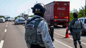 Policía de la Guardia Nacional mirando hacia un autobús que transita por la carretera.