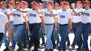 Se vea jóvenes marchando y vestidos de playera blanca y pantalón de mezclilla con cachucha.