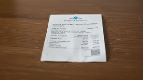 Se observa un escritorio de madera y ahí está un recibo blanco que dice Aguas de Saltillo.
