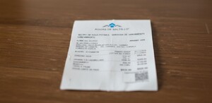 Se observa un escritorio de madera y ahí está un recibo blanco que dice Aguas de Saltillo.