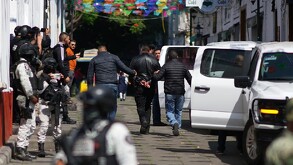 Autoridades llevando detenido a uno de los escoltas de Carlos Manzo con militares y múltiples personas alrededor