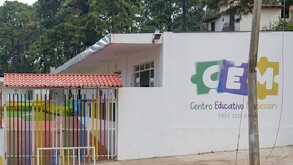 Vista de la fachada exterior del Centro Educativo Montessori en Mazamitla con barda blanca y postes de colores