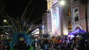 Imagen de la Virgen de Guadalupe y varias personas con disfraz de Danza Azteca