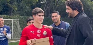 El dueño de Chivas, Amaury Vergara (a la derecha, de traje oscuro), pone la mano en el hombro del futbolista Jesús 