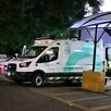 Vista lateral de una ambulancia de la Cruz Verde Las Águilas en Zapopan estacionada al exterior del hospital de noche con motos a los lados