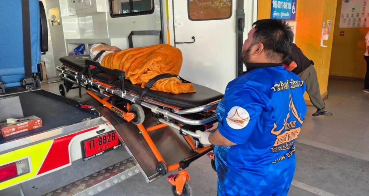 Paramédico tailandés subiendo a la mujer en una camilla con un cobertor naranja dentro de una ambulancia