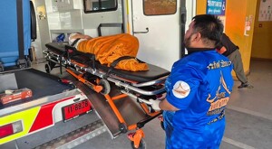Paramédico tailandés subiendo a la mujer en una camilla con un cobertor naranja dentro de una ambulancia