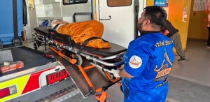 Paramédico tailandés subiendo a la mujer en una camilla con un cobertor naranja dentro de una ambulancia