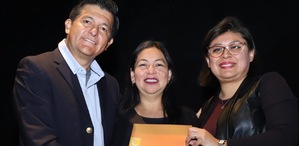 Dos hombres y una mujer parados en un fondo negro y sosteniendo una revista.