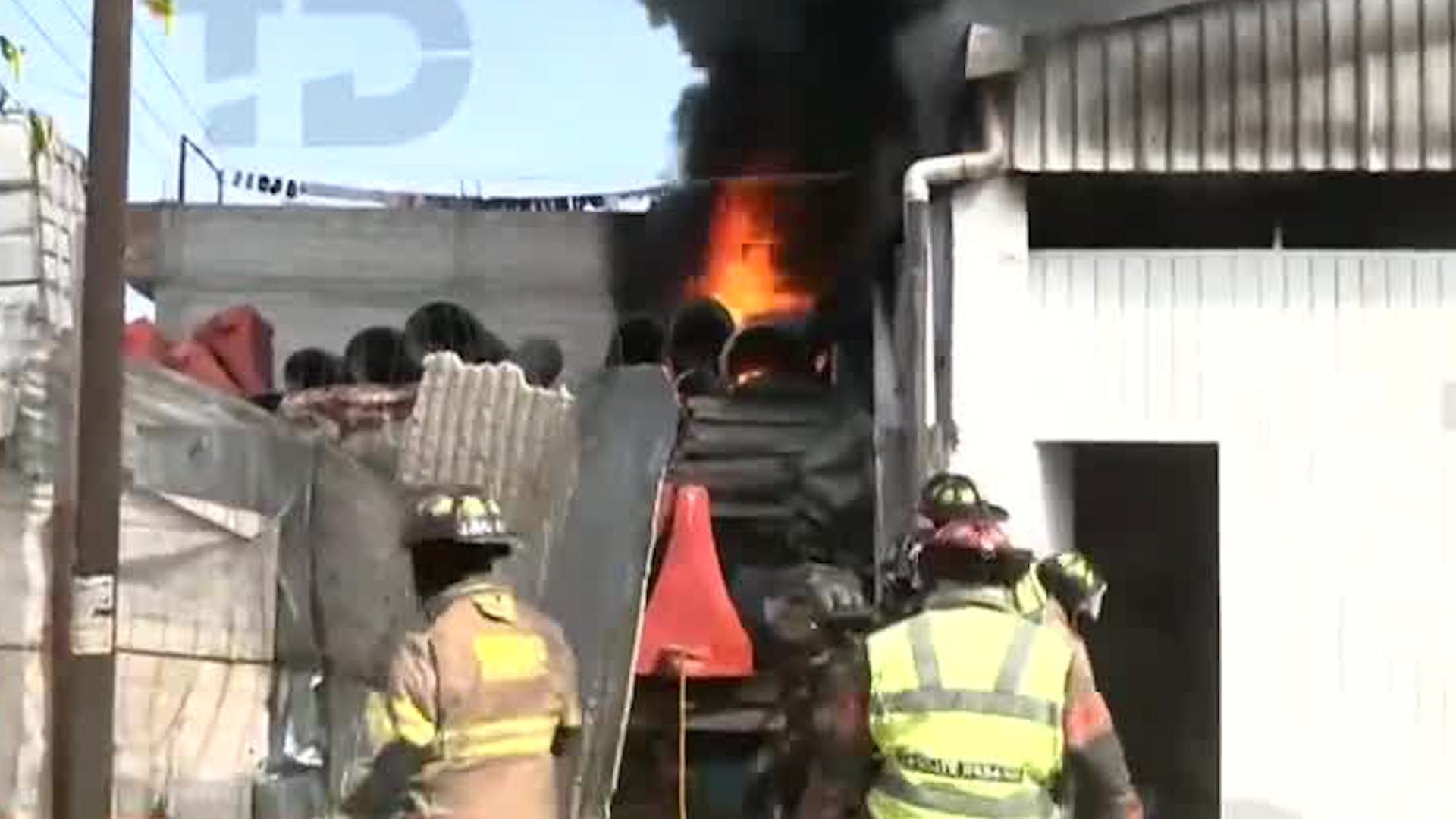 En la colonia Ejidos de San Cristóbal, bomberos del municipio de Ecatepec realizan labores para combatir el incendio en el almacén con tablas de madera.