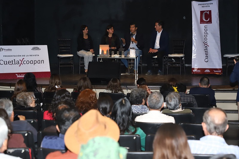 Personas presentando una revista ante una multitud de personas.