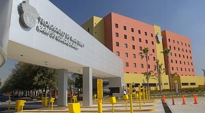 Vista de la fachada exterior, el estacionamiento y uno de los edificios color naranja con amarillo del Tec de Monterrey campus Guadalajara de día
