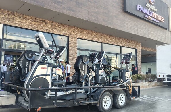 Varios aparatos de gimnasio están afuera de un gimnasio con letrero de Family Fitness.