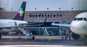 Dos aviones de Volaris estacionados en pista de aterrizaje del Aeropuerto de Guadalajara con trabajadores, escalera y pasajeros alrededor
