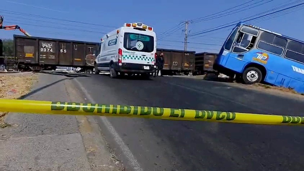 Ambulancia de la Cruz Verde de Tlajomulco estacionada a un lado del camión que fue impactado y una cinta policiaca en primer plano