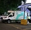 Vista lateral de una ambulancia de la Cruz Verde Las Águilas en Zapopan estacionada al exterior del hospital de noche con motos a los lados