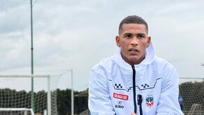 Primer plano de un joven futbolista (probablemente de Club León) con cabello rapado, vestido con una chaqueta deportiva blanca con el logo del equipo