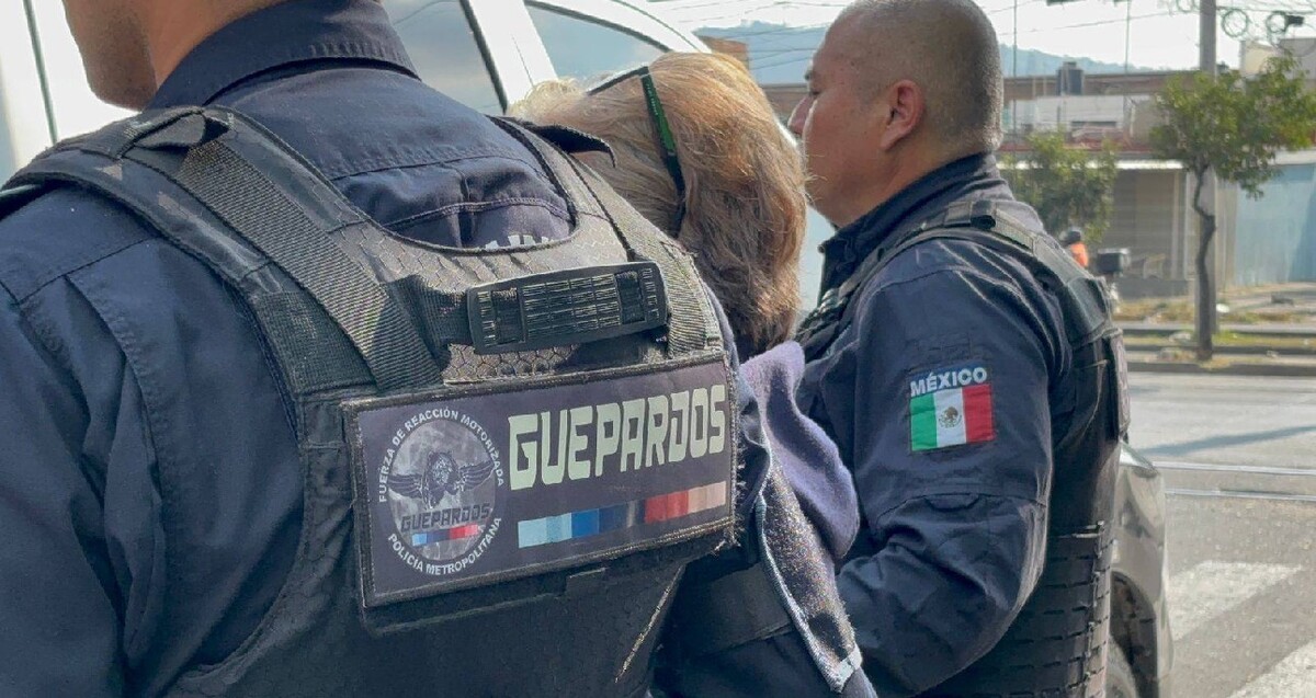 Oficiales de la Policía Metropolitana en Jalisco con el escudo de Guepardos en sus uniformes vistos de espaldas mientras detiene a una mujer