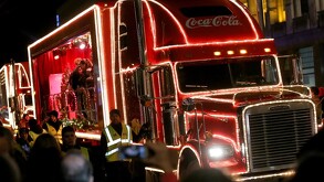 Se observa un camión de la Coca Cola color rojo con personas alrededor.