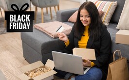 Mujer sentada en el piso haciendo compras en línea con una tarjeta en mano y una computadora portatil