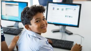 Imagen de un niño sentado frente a una computadora.