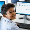 Imagen de un niño sentado frente a una computadora.