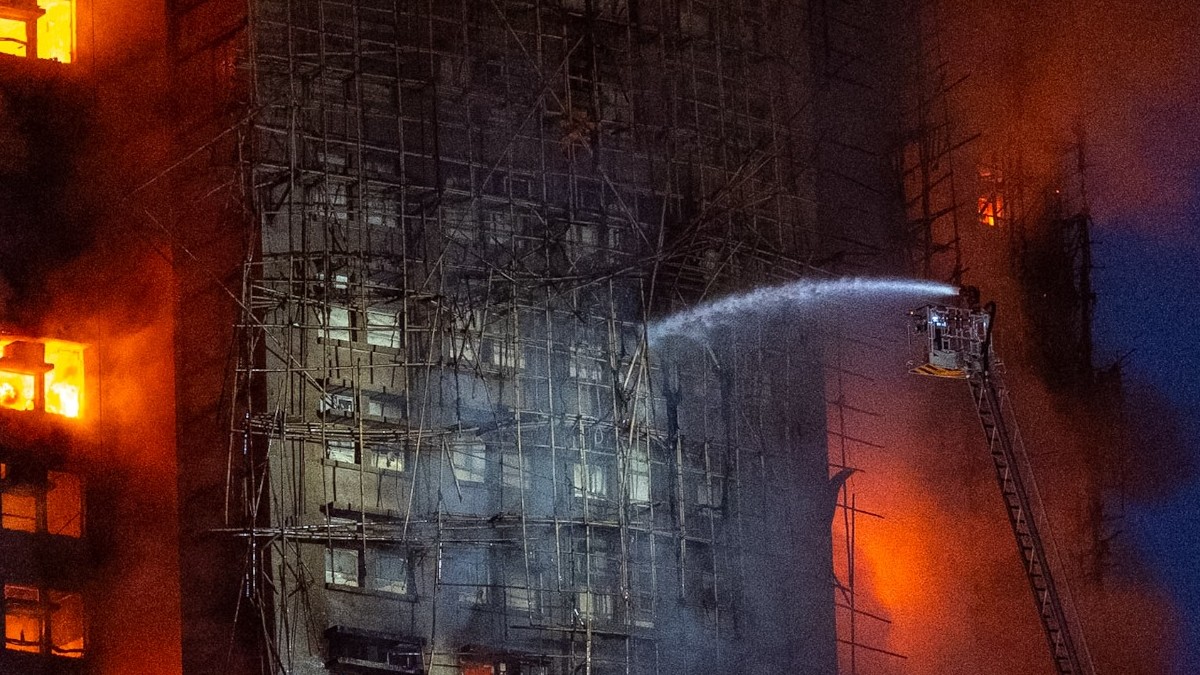 Edificios incendiándose junto a escalera con bomberos aventando agua