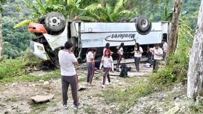 Jóvenes con uniforme escolar alrededor de un autobús volcado en Veracruz.