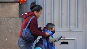 Madre despidiendo a su hijo en la entrada a la escuela.