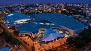 Vista aérea nocturna de la Expo Guadalajara, el gran centro de convenciones y exposiciones, con su icónico techo abovedado iluminado en el centro.