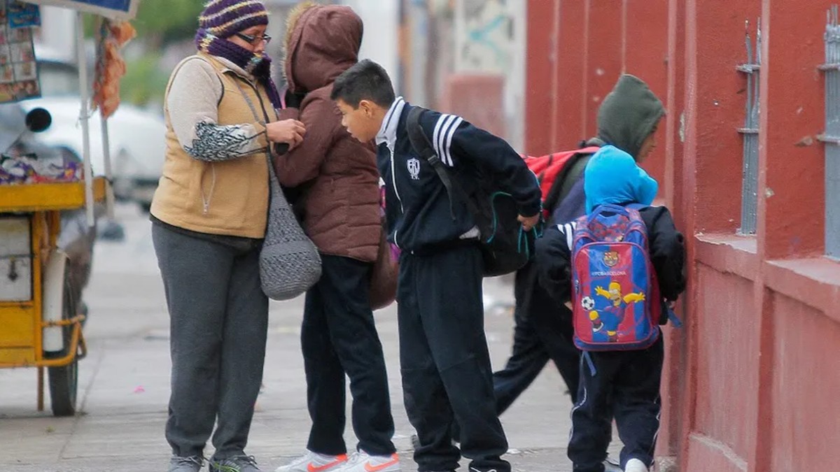 Estudiantes con frío afuera de escuela.